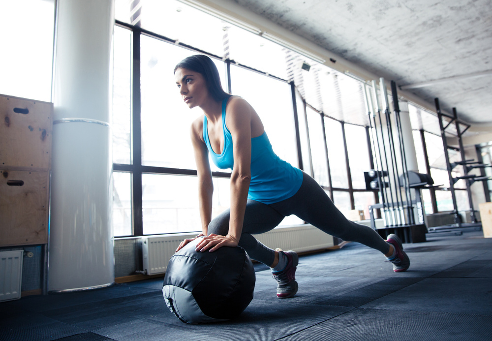 Young woman doing exercise with fit ball at gym